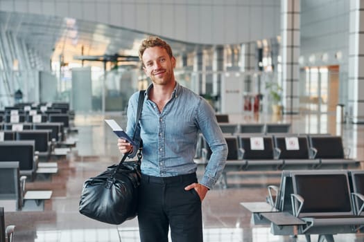 Young man in formal wear is in modern airport. Conception of vacation.