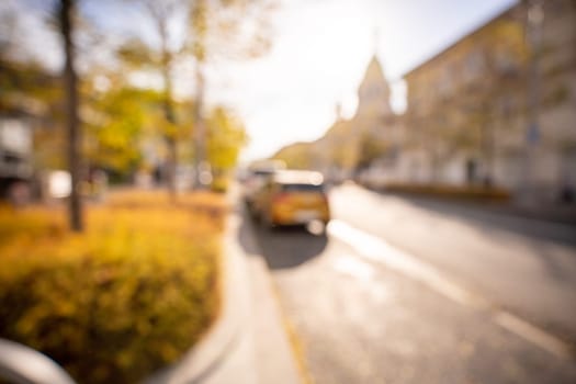 Autumn season bokeh background. Abstract city blur along the road with cars