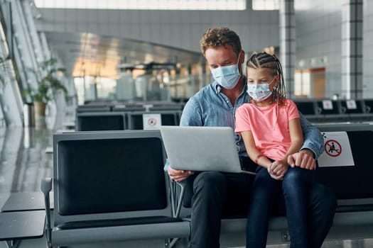 With little girl. Young man in formal wear is in modern airport.