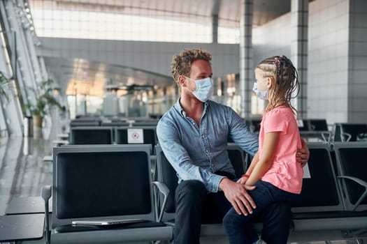 With little girl. Young man in formal wear is in modern airport.