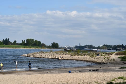 Three children in bathing suits play on the bank of Rhine in Duesseldorf, Germany