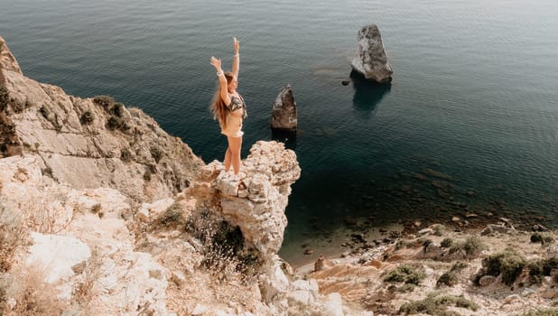 Woman travel sea. Happy tourist taking picture outdoors for memories. Woman traveler looks at the edge of the cliff on the sea bay of mountains, sharing travel adventure journey.