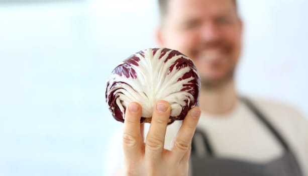 Smiling chef holding red cabbage. Benefits of vegetarian food concept