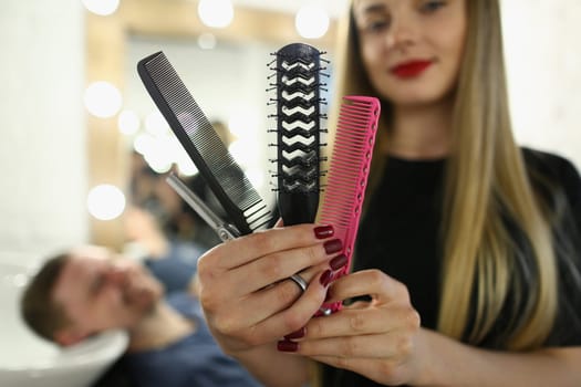 Woman hairdresser holding set of combs and scissors in a barbershop. Hairdressing tools concept