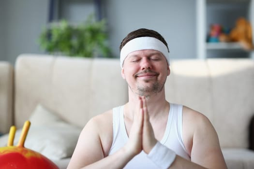 Handsome athletic young man presses hands to chest in namaste nirvana pose. Patience and calmness relieves stress in meditation and does yoga