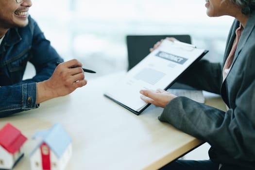 Guarantee Insurance Sign a contract, couple a smiling couple is signing a contract to invest in real estate with the Mortgage officer with the bank.