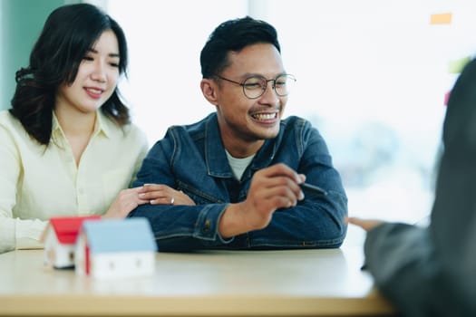 Guarantee Insurance Sign a contract, couple a smiling couple is signing a contract to invest in real estate with the Mortgage officer with the bank.