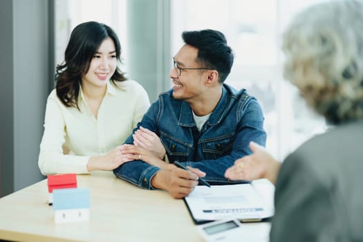 Guarantee Insurance Sign a contract, couple a smiling couple is signing a contract to invest in real estate with the Mortgage officer with the bank.