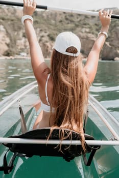 Woman in kayak back view. Happy young woman with long hair floating in transparent kayak on the crystal clear sea. Summer holiday vacation and cheerful female people having fun on the boat.