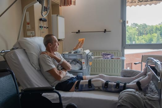 a man with a broken leg in an orthese in bed in a clinic after an accident, High quality photo