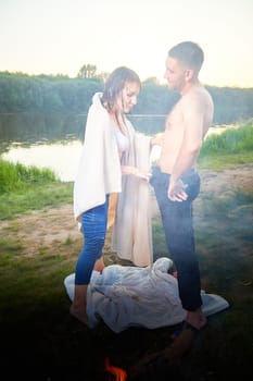 Happy Couple Outdoor relaxin and having fun on nature in the park in summer evening with smog and fog. Family or lovers have date and rest outdoors. Girl takes off jeans from man or guy