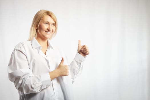 Portrait of a pretty blonde smiling woman posing on white background. Happy girl model in white shirt in studio. Lady winner is joyfull. Copy space