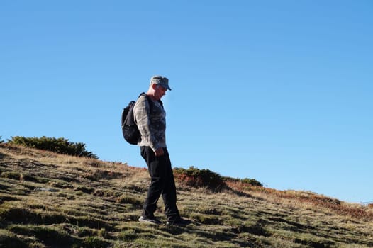 a man with a backpack walks along a mountain path.