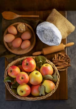 Top view on a ripe apples on a wooden table in basket with ingredients for pie near