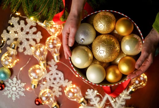 Female hands holding Merry Christmas gift box on red decorated festive background, top view