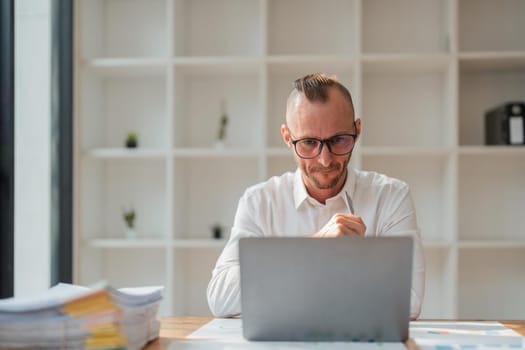 Business man working at office with laptop and documents on his desk.