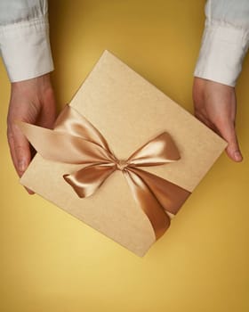 On a yellow flat background hands hold a gift