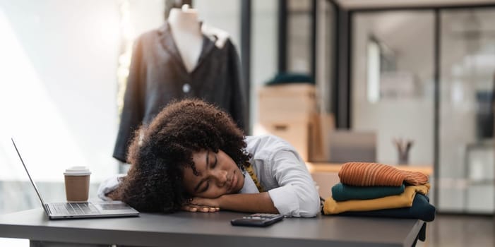 People tailor working in fashion design concept. Young adult asian designer woman tried and sleeping at workshop table. Background in business start up studio dressmaker...