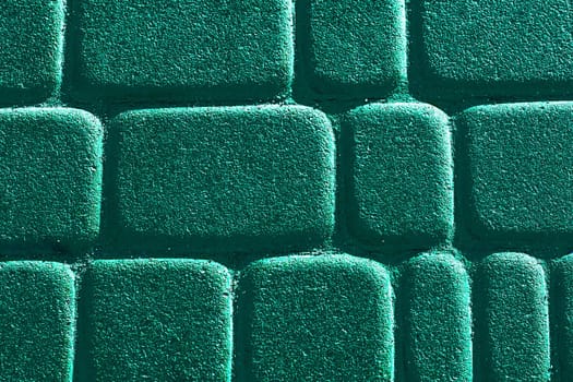 a wide way leading from one place to another, especially one with a specially prepared surface which vehicles can use. Emerald brick road with sunny shine.Cobblestones on the pavement close-up