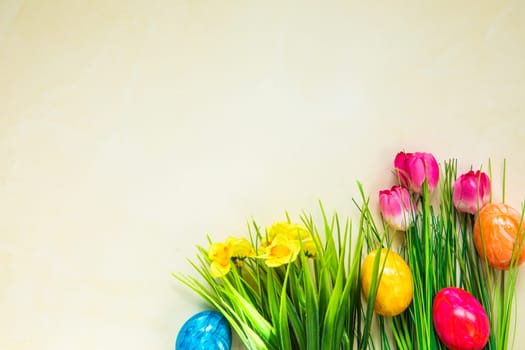Colorful easter eggs with flowers and green grass. Easter eggs disappear on light yellow background. Easter Holiday, egg hunting concept top view