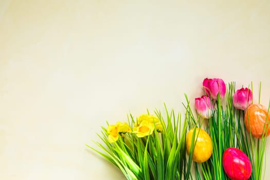 Colorful easter eggs with flowers and green grass. Easter eggs disappear on light yellow background. Easter Holiday, egg hunting concept top view