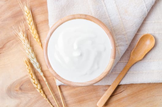 Fresh greek yogurt in wooden bowl with wooden spoon. Healthy breakfast.
