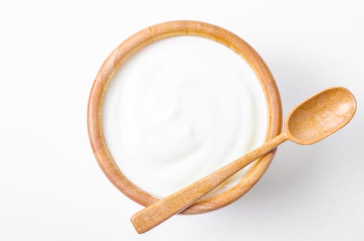 Fresh greek yogurt in wooden bowl with wooden spoon on white background. Healthy breakfast.