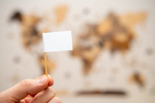 White flag with copy space in man hands with world map on the background.