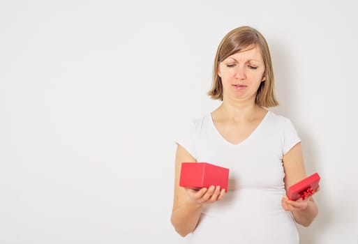 Sad unhappy woman on the white background opening a red present box for the Valentines day. High quality photo.