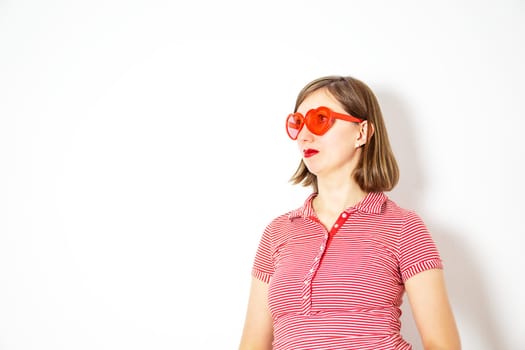 Portrait of the young beautiful woman with red heart sunglasses on the white background. High quality photo.