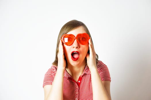 Valentines Day portrait of young smiling surprised woman in red sunglasses on the white background. High quality photo.