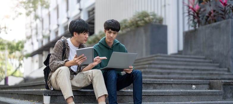 Happy Asian man college student playing mobile game on his smartphone with his friend..