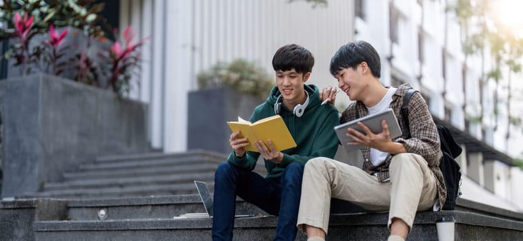 Happy Asian man college student playing mobile game on his smartphone with his friend..