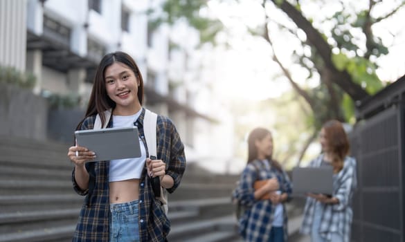 young happy attractive asian student smiling and looking at camera with friends on outdoor university background. Asian woman in self future education or personalized learning concept...