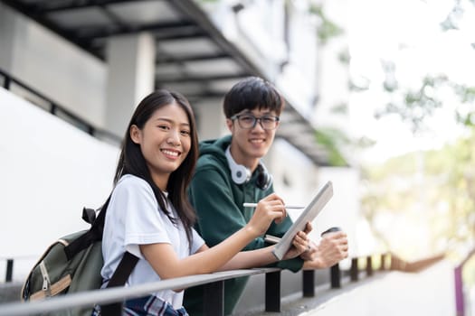 Group of Asian college student reading books and tutoring special class for exam on grass field at outdoors. Happiness and Education learning concept. Back to school concept. Teen and people theme...