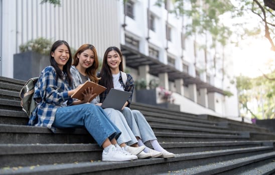 Group of Asian college student reading books and tutoring special class for exam on grass field at outdoors. Happiness and Education learning concept. Back to school concept. Teen and people theme...