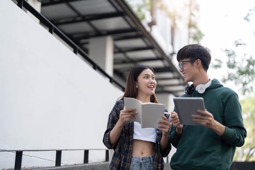 Group of Asian college student reading books and tutoring special class for exam on grass field at outdoors. Happiness and Education learning concept. Back to school concept. Teen and people theme...