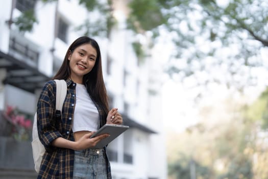 Female college students happily holding laptops outdoors after school on campus. when the sun goes down the horizon with warm light..