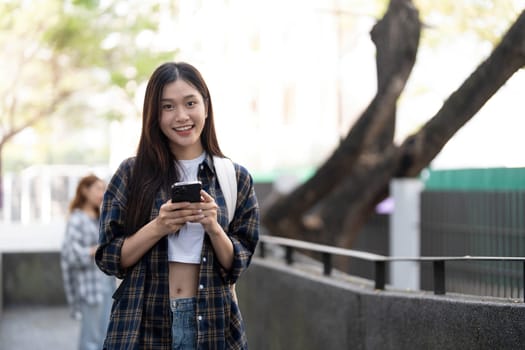 young happy attractive asian student smiling and looking at camera with friends on outdoor university background. Asian woman in self future education or personalized learning concept...