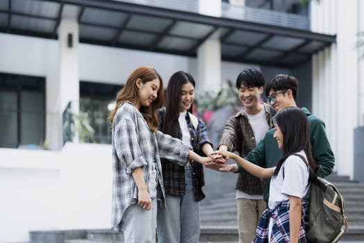 Group of happy Asian college students putting their hands together. success team building concept..