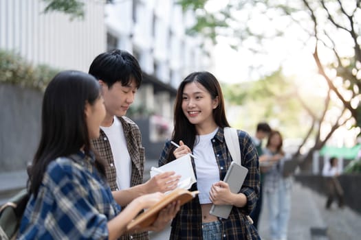 Group of Asian college student reading books and tutoring special class for exam on grass field at outdoors. Happiness and Education learning concept. Back to school concept. Teen and people theme...