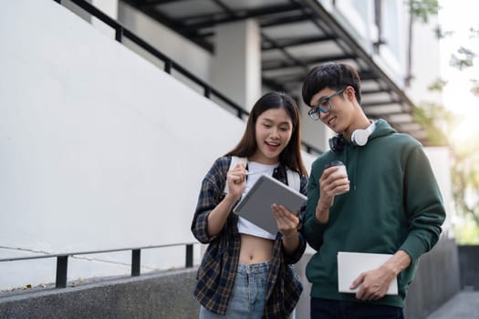 Group of Asian college student reading books and tutoring special class for exam on grass field at outdoors. Happiness and Education learning concept. Back to school concept. Teen and people theme...