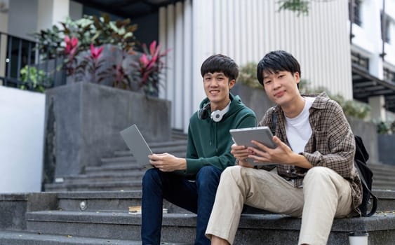 Happy Asian man college student playing mobile game on his smartphone with his friend..