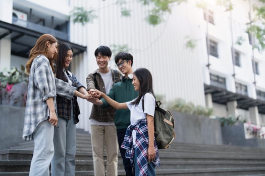 Group of happy Asian college students putting their hands together. success team building concept..