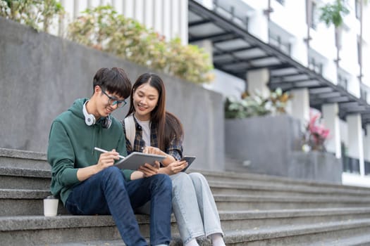 Group of Asian college student reading books and tutoring special class for exam on grass field at outdoors. Happiness and Education learning concept. Back to school concept. Teen and people theme...