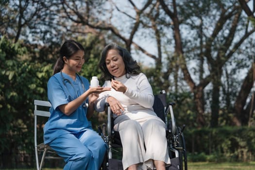 Female nurse doing blood pressure measurement of a senior woman patient. Doctor checking blood pressure of an elderly woman at garden home. Female caregiver and senior woman together