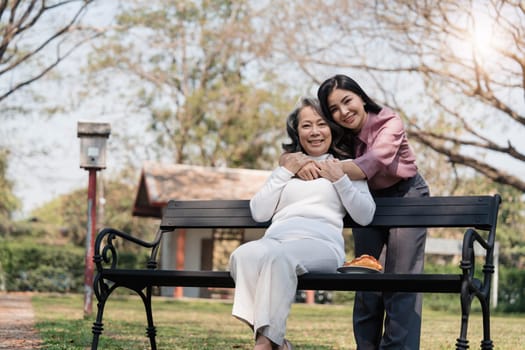 Happy adult granddaughter and senior grandmother having fun enjoying talk sit with green nature. in park..