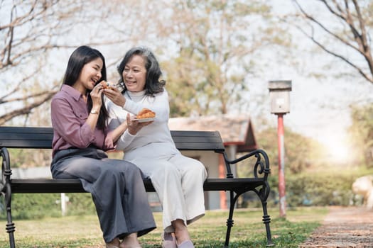 Happy adult granddaughter and senior grandmother having fun enjoying talk sit with green nature. in park..