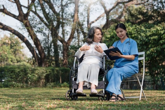 Female nurse doing blood pressure measurement of a senior woman patient. Doctor checking blood pressure of an elderly woman at garden home. Female caregiver and senior woman together