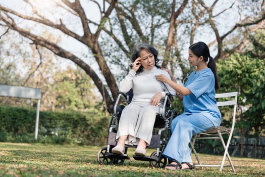 Female nurse doing blood pressure measurement of a senior woman patient. Doctor checking blood pressure of an elderly woman at garden home. Female caregiver and senior woman together